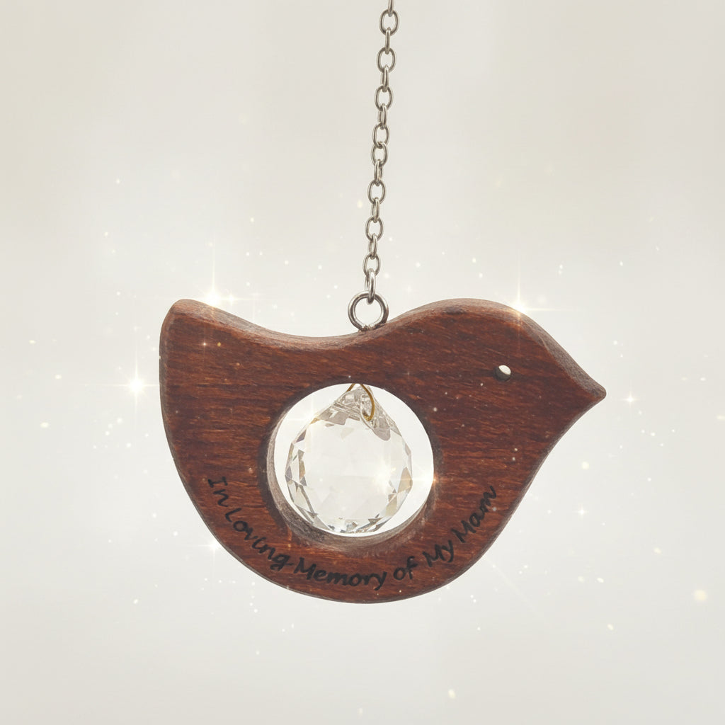 A wooden bird-shaped pendant necklace displayed on a beige fabric jewelry bust. The pendant is made of dark brown wood with a circular cutout in the center containing a faceted clear crystal.
